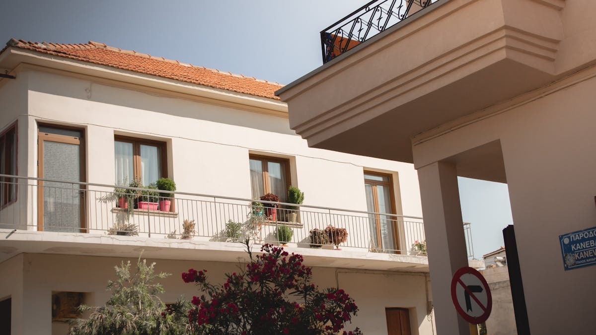 Traditional Greek house facade with potted plants and balcony details.